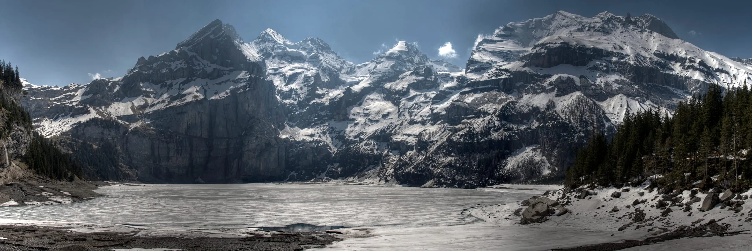 Zugefrorener Oeschinensee im Winter, umgeben von schneebedeckten Bergen