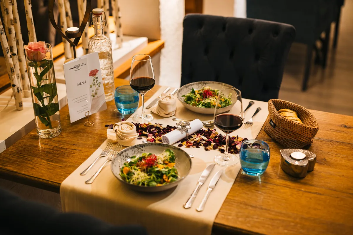 Gedeckter Tisch im Restaurant des Chalet-Hotel Adler mit Kerzenlicht und Rosenblättern